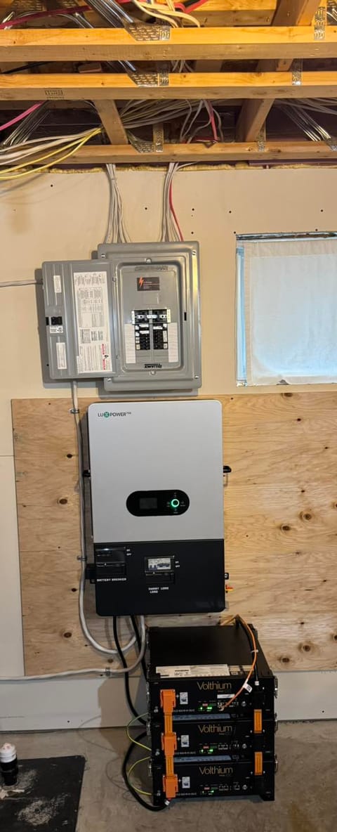 Système de batteries de secours résidentiel : onduleur mural, modules au lithium empilés et panneau secondaire, installés au sous-sol